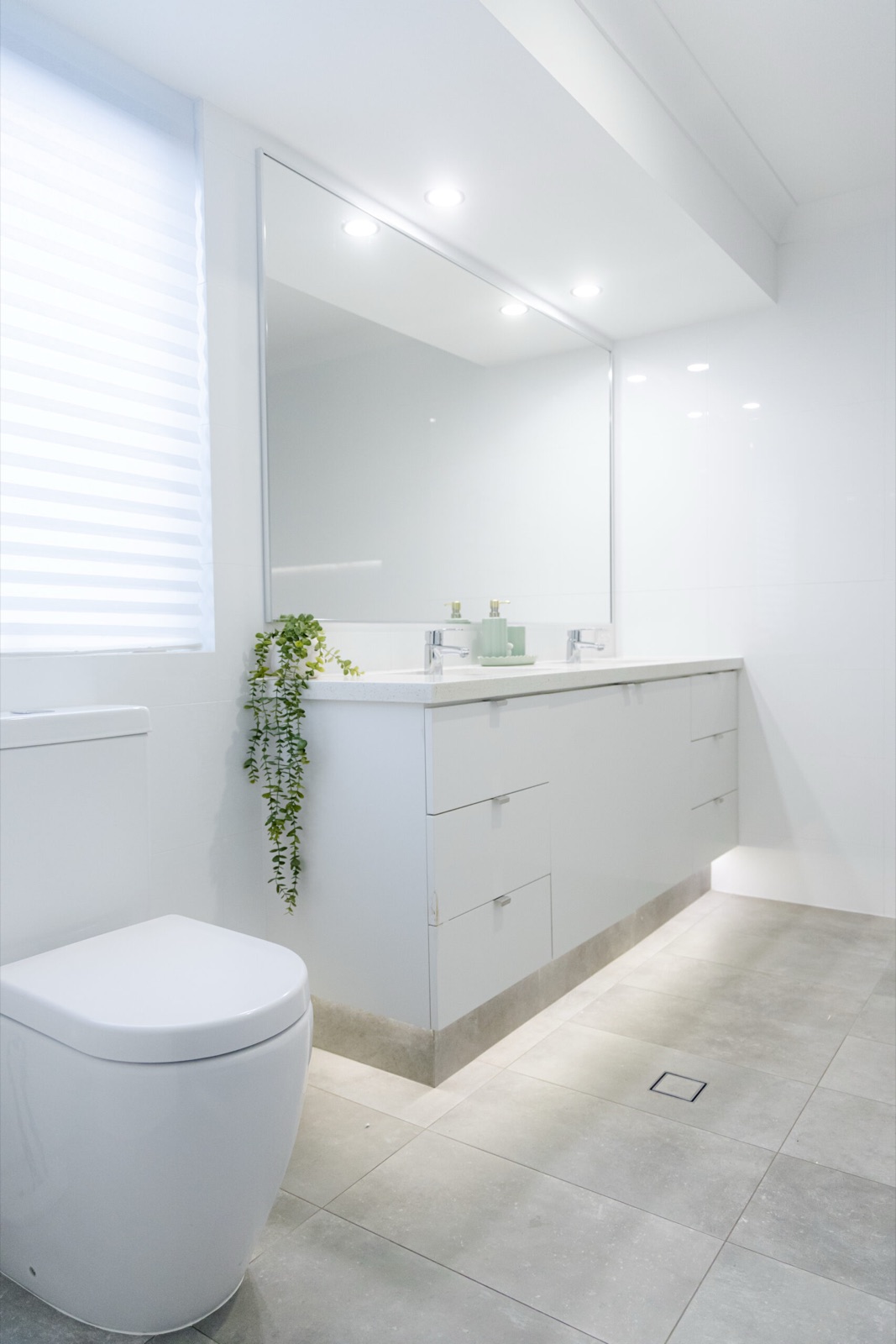 Bright white bathroom with vanity, mirror and grey floor tiles